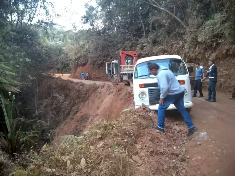 Veículo branco, à beira de uma ribanceira, é observado por um homem, em primeiro plano. Ao fundo mais dois homens e um caminhão-guindaste. A falta de obras de manutenção da estrada do Salto, traz perigos para os moradores do distrito que precisam se deslocar até à sede do município.