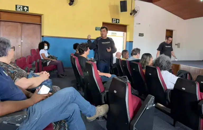 De pé, tendo ao seu redor pessoas que participaram do evento, um homem, de pé, fa intervenção durante seminário sobre plano de manejo de sítios arqueológicos faz intervenção