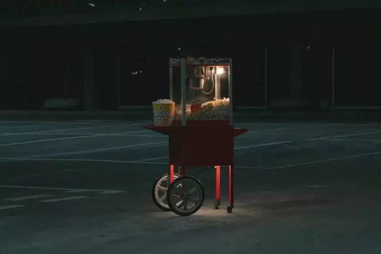 Carrinho de pipoca vermelho em um local com pouca iluminação
