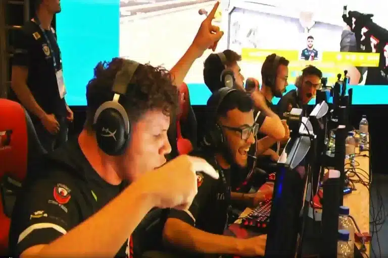 Equipe de jogadores de eSports, diante de telas de computador, durante disputa de partida.
