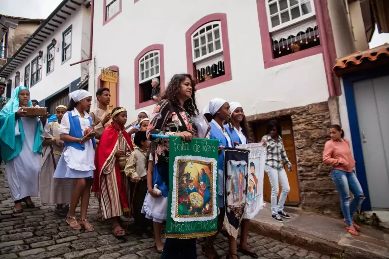 Grupo de mulheres e crianças, descendo uma rua, na tradicional Folia de Reis