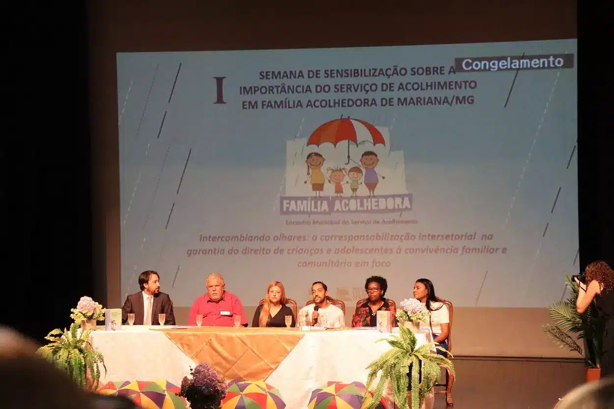 Mesa de abertura do evento sobre acolhimento em família acolhedora, composta por Luís Delazzari, Edson Agostinho Daniely Alves, Pedro Paulo Telles Leão, Maria Cristina Pereira e Elizamar Barbosa Martins (da esquerda para a direita)